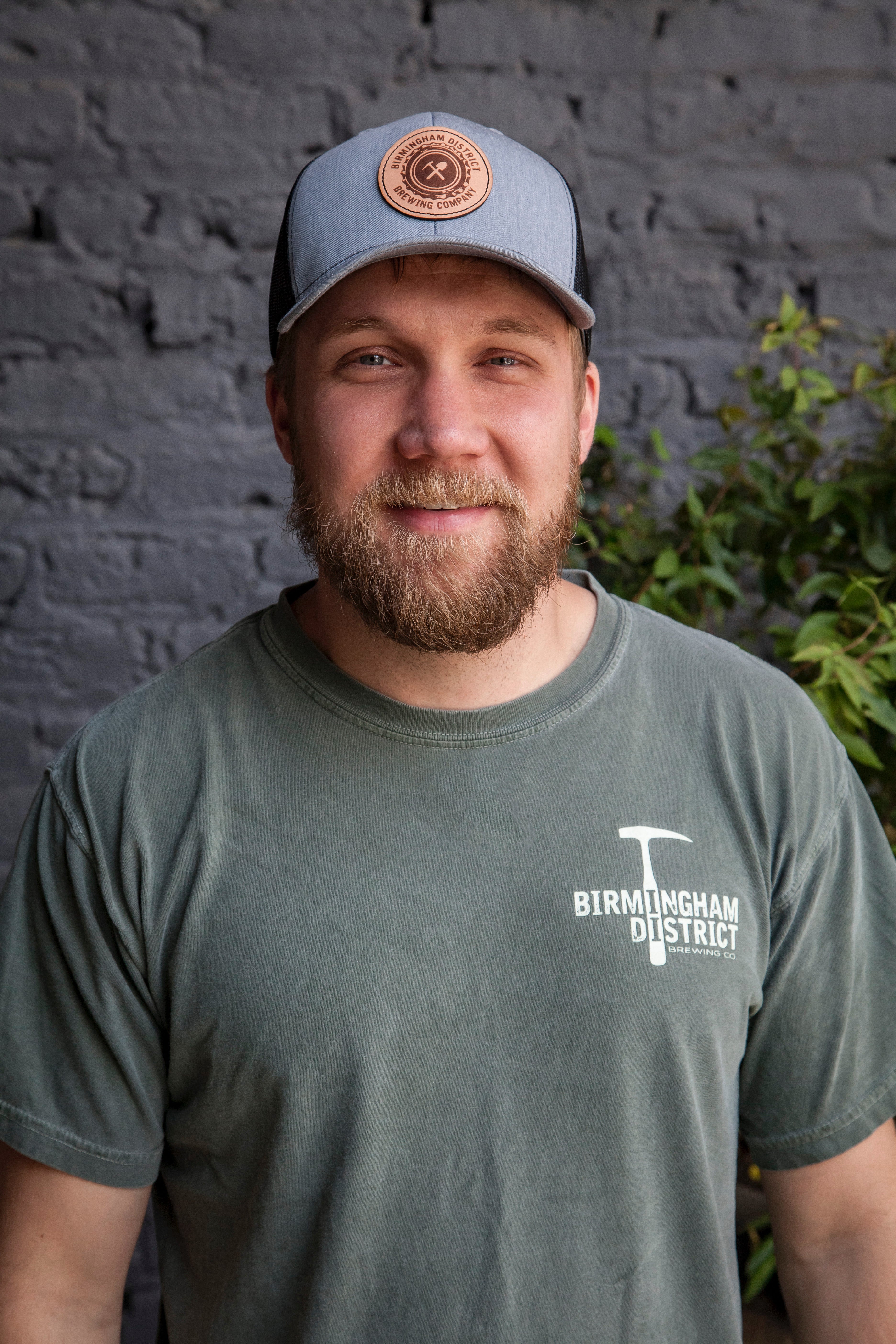Customer wearing Birmingham District Brewing leather patch trucker cap and pickaxe logo tee, lifestyle photo, by Presto Embroidery