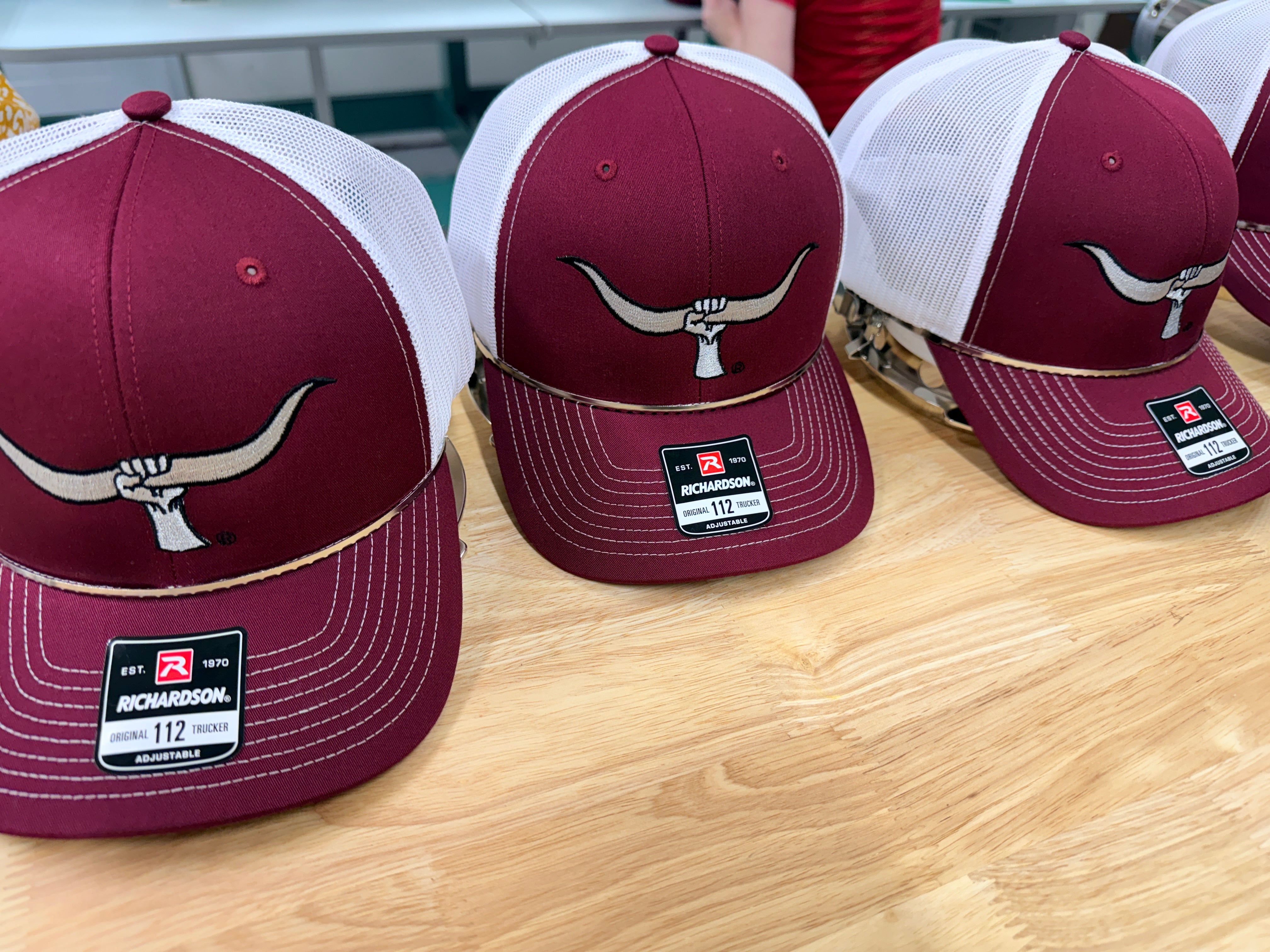 Custom embroidered maroon and white longhorn skull logo trucker caps, run on Richardson 112 blanks by Presto Embroidery Birmingham