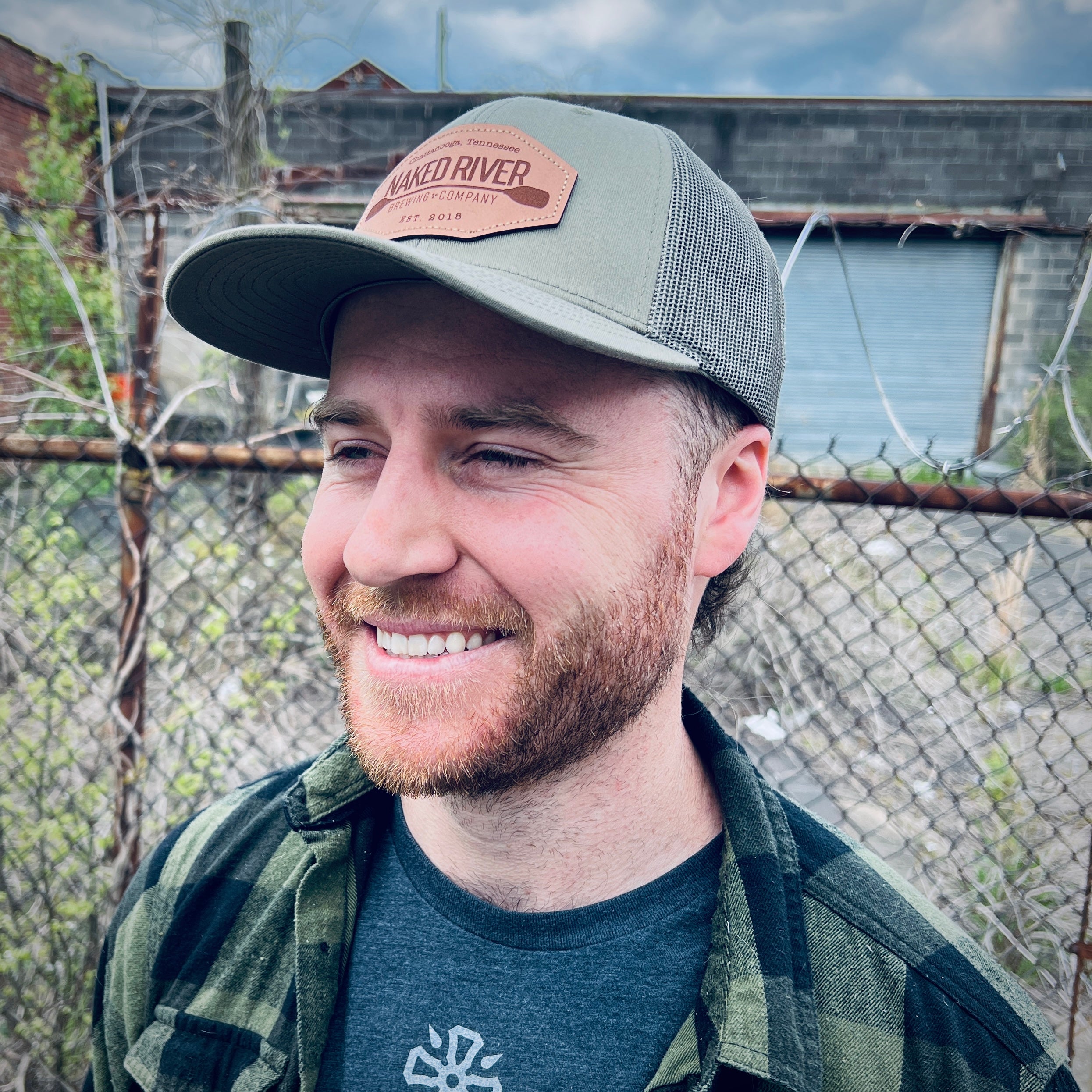 Naked River Brewing Company embroidered leather patch trucker cap worn outdoors, stitched at Presto Embroidery Birmingham AL