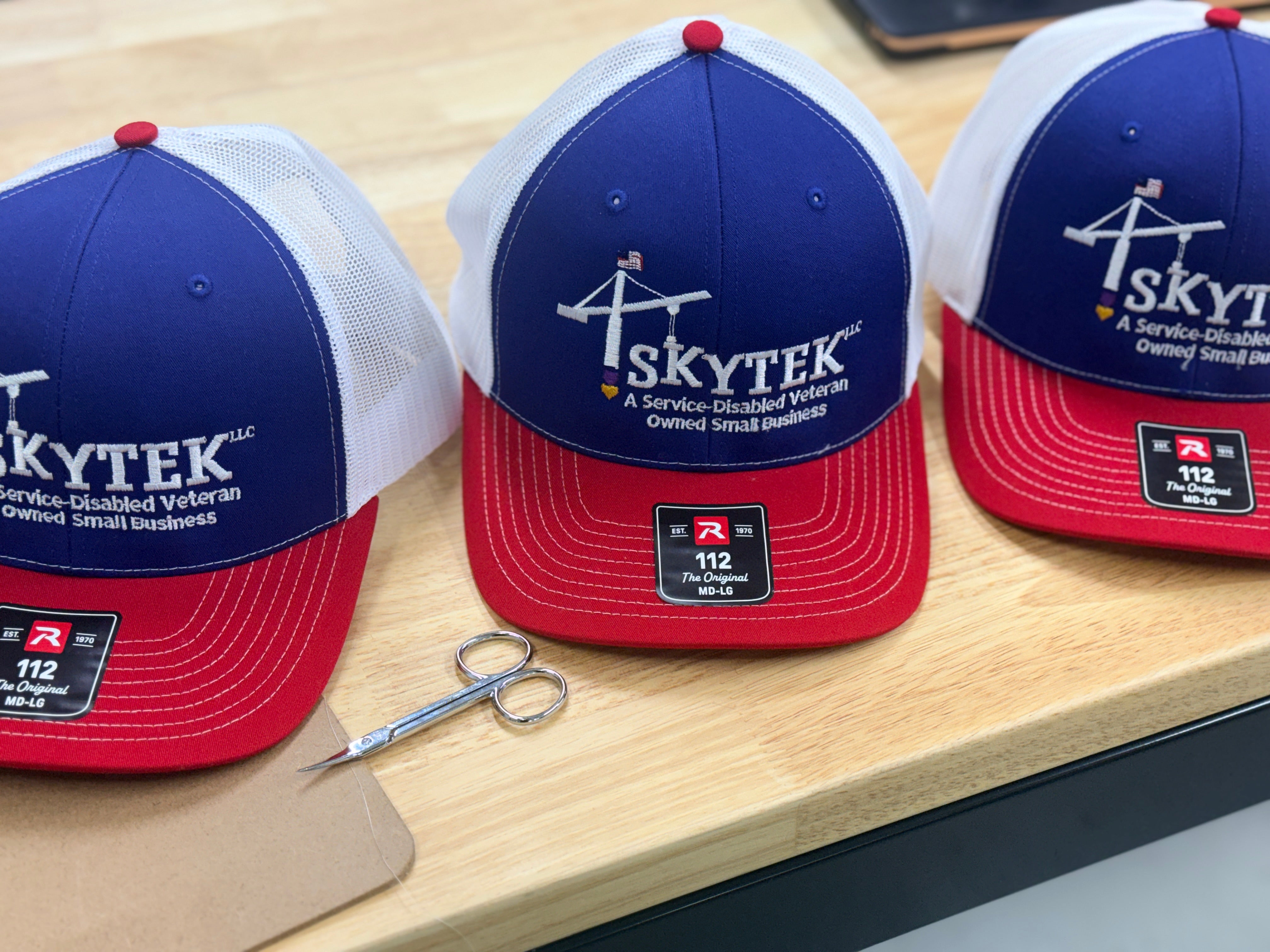 SkyTek service-disabled veteran-owned small business custom embroidered red, white and blue trucker caps with American flag detailing, by Presto Embroidery