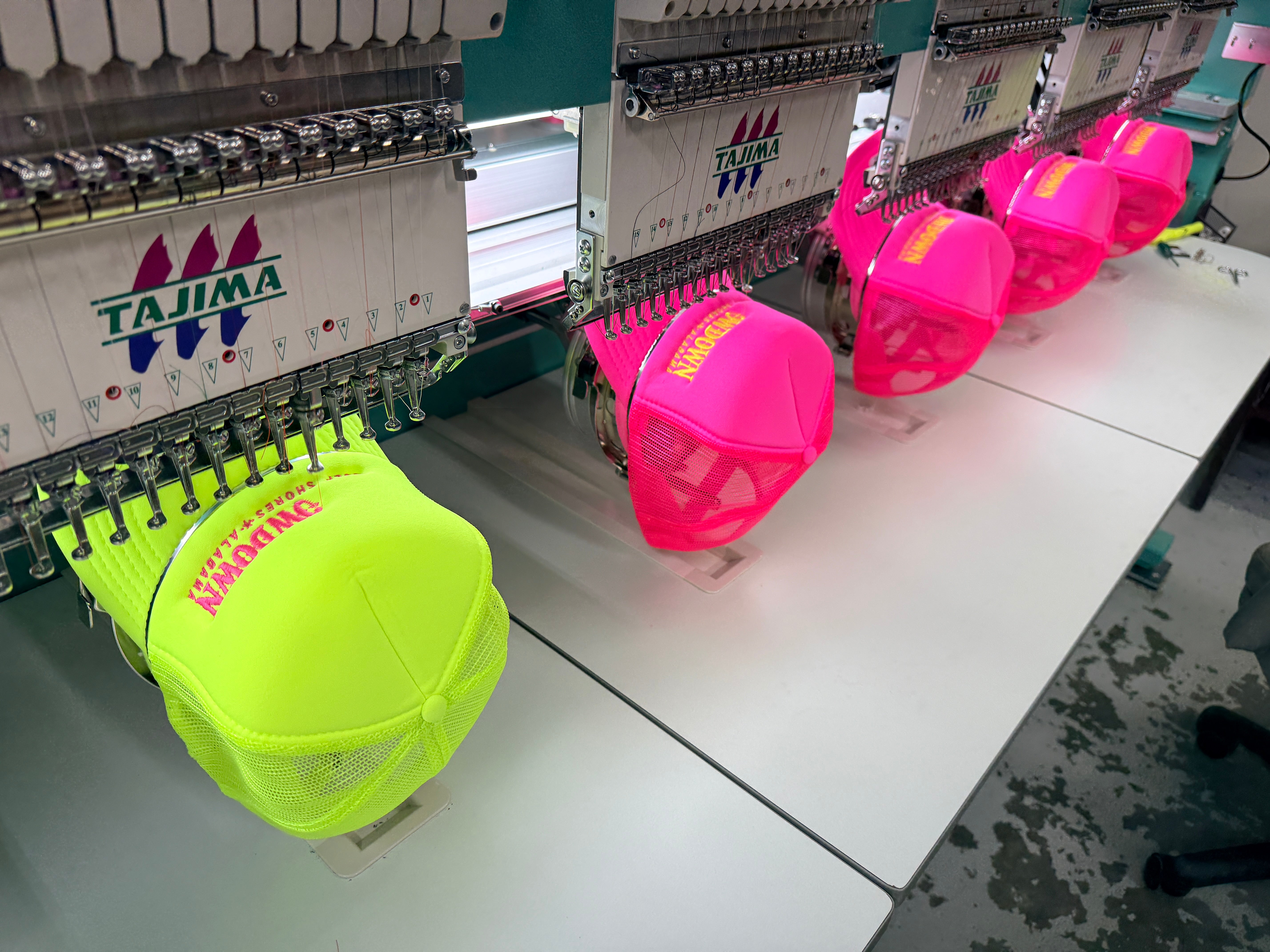 Tajima multi-head commercial embroidery machine in production at Presto Embroidery Birmingham, stitching neon yellow and pink trucker caps